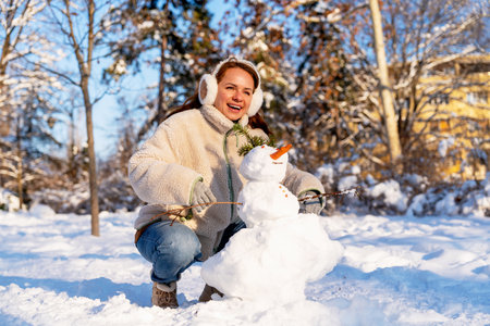 Joyful woman making snowman outdoors in winterの写真素材