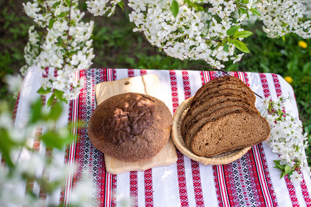 Rye bread on a wooden board against a background of with blooming cherry branches. fresh bread on a...