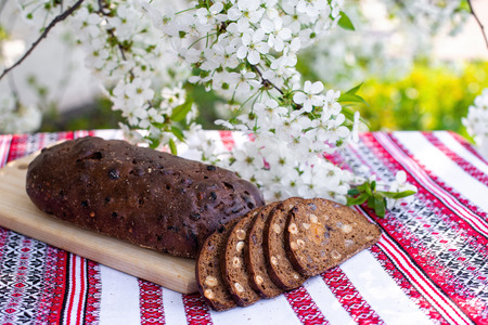 Rye bread on a wooden board against a background of with blooming cherry branches. fresh bread on a...