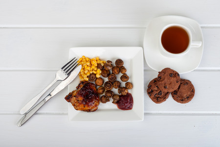 a plate of food and a cup of tea on a white wooden background