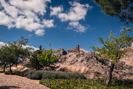 A stone path leads through greenery toward a lone watchtower perched atop Marvao's rocky crest.の写真素材