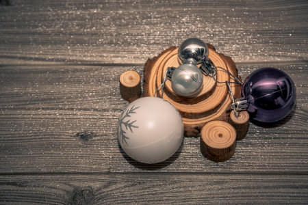 Purple, silver and white Christmas baubles arranged on rustic wooden slices over glitter wooden background, festive still life with copy space.の写真素材