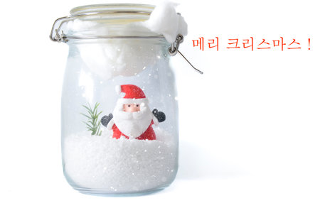 Santa Claus in snowy glass jar with Korean Merry Christmas lettering on white background, festive winter greeting card concept.の写真素材