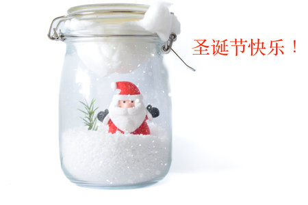 Santa Claus figure in snowy glass jar with Chinese Merry Christmas characters on clean white background, modern multilingual Christmas card.の写真素材