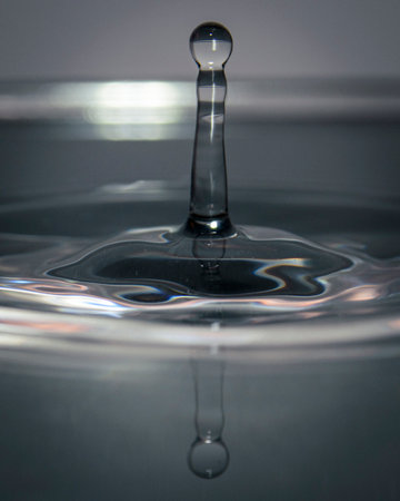 Minimalist scene of two aligned water droplets above soft ripples, symbolizing balance, focus and...