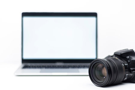 Minimal high-key scene with DSLR lens and laptop with blank screen. Concept for photography business, editing workflow and technology with copy space.の写真素材