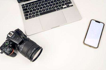 Flat lay of laptop, DSLR camera and smartphone with blank screen on white background, minimal workspace with copy space.の写真素材