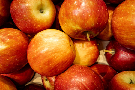 Close-up of red apples in a supermarket box, full frame fruit texture background with warm tones.