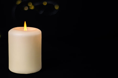 Lit pillar candle on dark background with large copy space, cozy ambience and relaxation concept.の写真素材