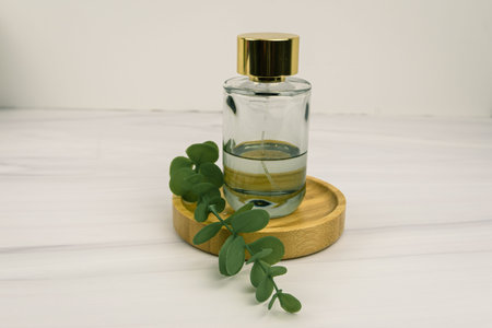 Wellness product still life: clear aromatherapy or perfume bottle with gold cap on bamboo tray and...
