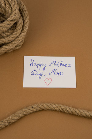 Handwritten Mother's Day greeting card with heart on brown kraft paper, framed by rustic rope and...