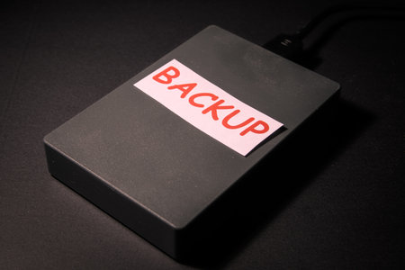External hard drive labeled backup on a dark desk, conceptual image of data backup, storage,...