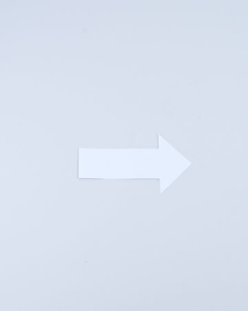 Single white paper arrow pointing right on a clean background, minimalist concept for direction, progress, navigation, choice and decision making.の写真素材