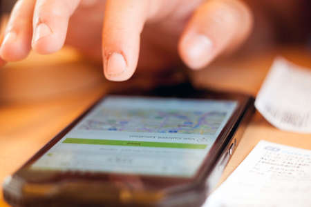 Finger presses the search button on the touch phone next are ticketsの写真素材