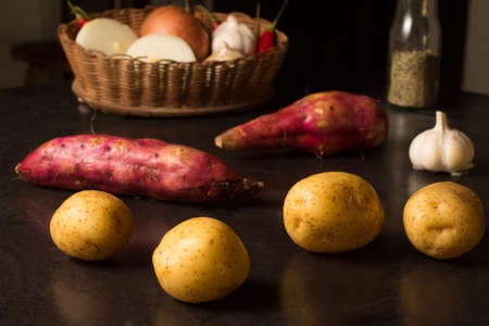 Potatoes and Sweet Potatoes over a wooden tableの写真素材