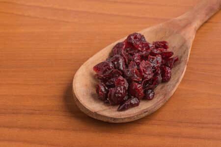 Dried Cranberries into a spoon over a wooden tableの写真素材