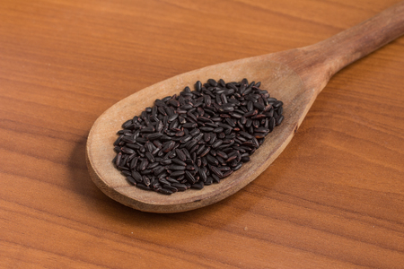 Black Rice into a Spoon over a wooden tableの写真素材