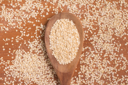 Quinoa Flakes into a spoon over a wooden table.の写真素材