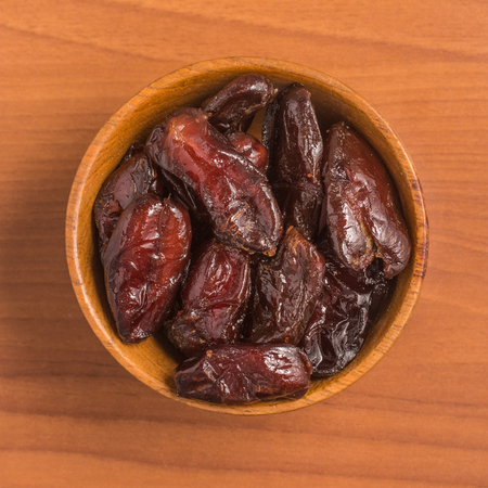 Dried Dates into a bowl. Tamara over a wooden tableの写真素材
