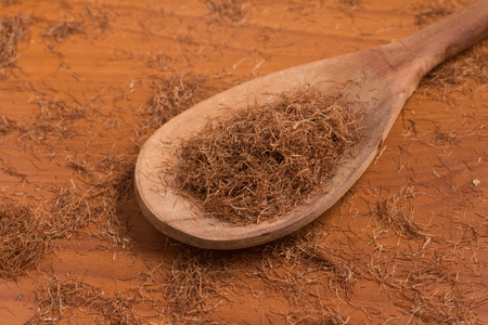 Dry Corn Silk Herb into a spoon over a wooden table.