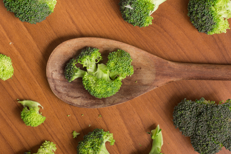 Broccoli into a spoon over a wooden tableの写真素材