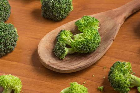 Broccoli into a spoon over a wooden tableの写真素材