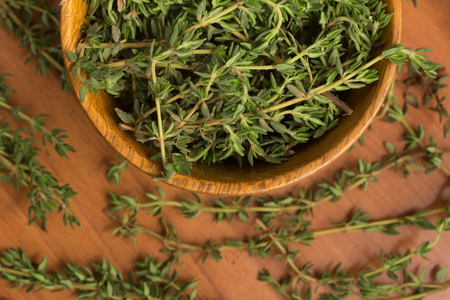 Fresh Thyme into a bowl over a wooden tableの写真素材