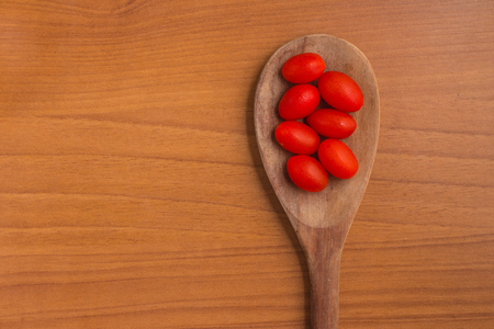 Cherry Tomatoes into a spoon over a wooden tableの写真素材