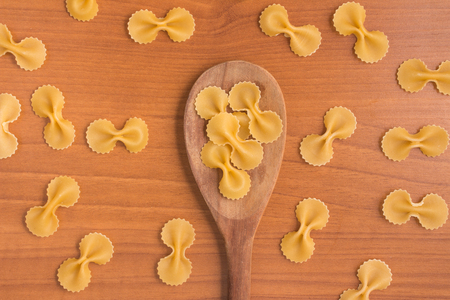 Farfalle into a spoon over a wooden tableの写真素材