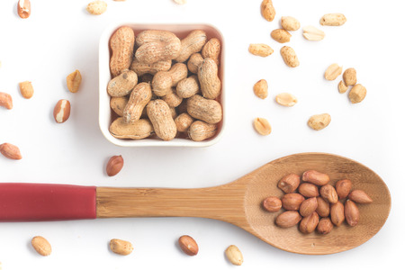 Peanuts pile. Shell Seeds into a spoon isolated on white backgroundの写真素材