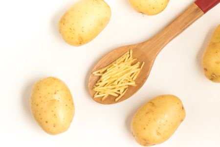Potato Sticks into a spoon on white background