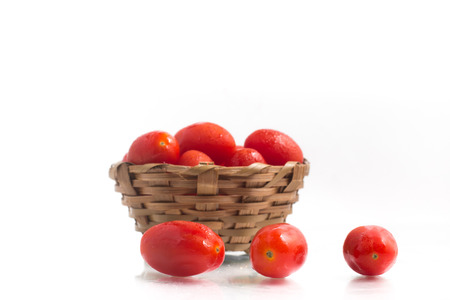 Cherry Tomatoes into a basket over a white backgroundの写真素材