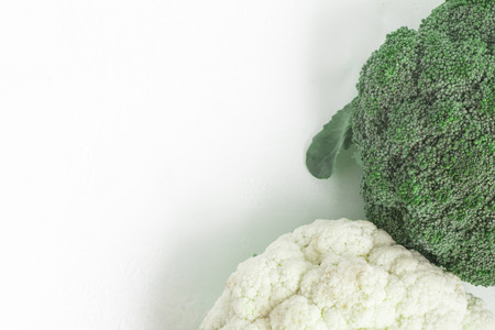 Fresh Whole Broccoli and couliflower Frame over a wet glass surfaceの写真素材
