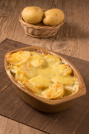Gratin potatoes in rustic dish over a wooden tableの写真素材
