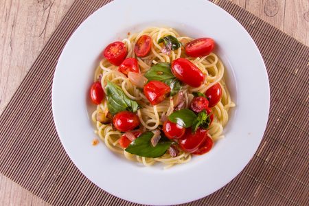 Spaghetti with cherry tomatoes over a wooden tableの写真素材
