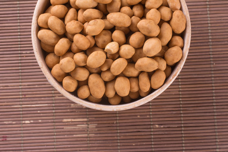 Japanese Peanuts into a bowl over a wooden table