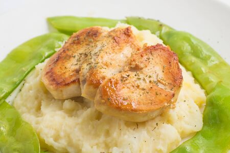 Mashed potatoes with chicken fillet and green peas on white backgroundの写真素材