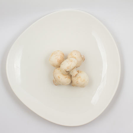 Fresh champignon mushroom on a plate on white backgroundの写真素材