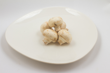 Fresh champignon mushroom on a plate on white backgroundの写真素材