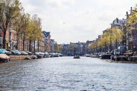 AMSTERDAM, NETHERLANDS - APRIL 14, 2019: Houses and Boats on Amsterdam Canal, Netherlands.のeditorial素材