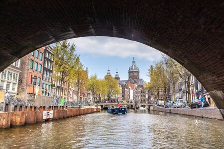 AMSTERDAM, NETHERLANDS - APRIL 14, 2019: Houses and Boats on Amsterdam Canal, Netherlands. Trip Boatのeditorial素材