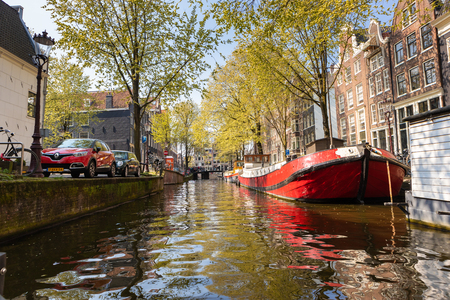 AMSTERDAM, NETHERLANDS - APRIL 14, 2019: Houses and Boats on Amsterdam Canal with a blue skyのeditorial素材