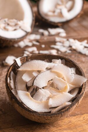 Shaved Coconut into a coconut bowl over a wooden tableの写真素材