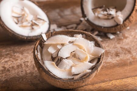 Shaved Coconut into a coconut bowl over a wooden tableの写真素材