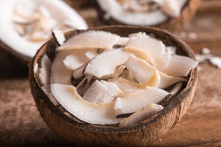 Shaved Coconut into a coconut bowl over a wooden tableの写真素材