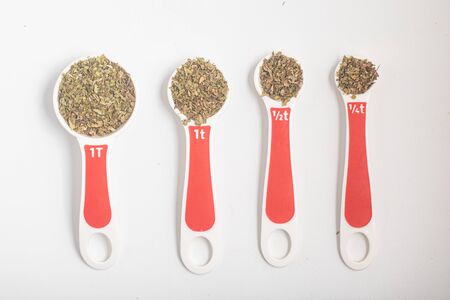 Dried Oregano into a Teaspoon and Tablespoon on white backgroundの写真素材