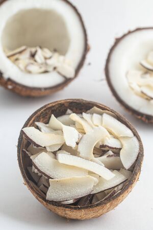 Shaved Coconut into a coconut bowl over white backgroundの写真素材