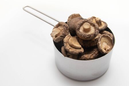 Dried Shitake Mushroom   into a measuring cup on white backgroundの写真素材