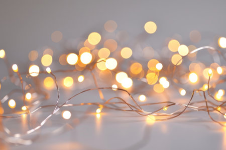 Warm white fairy lights on a light surface. Cozy and festive atmosphereの素材