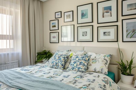 Bright bedroom with white pillows and blankets, framed art on the wallの素材